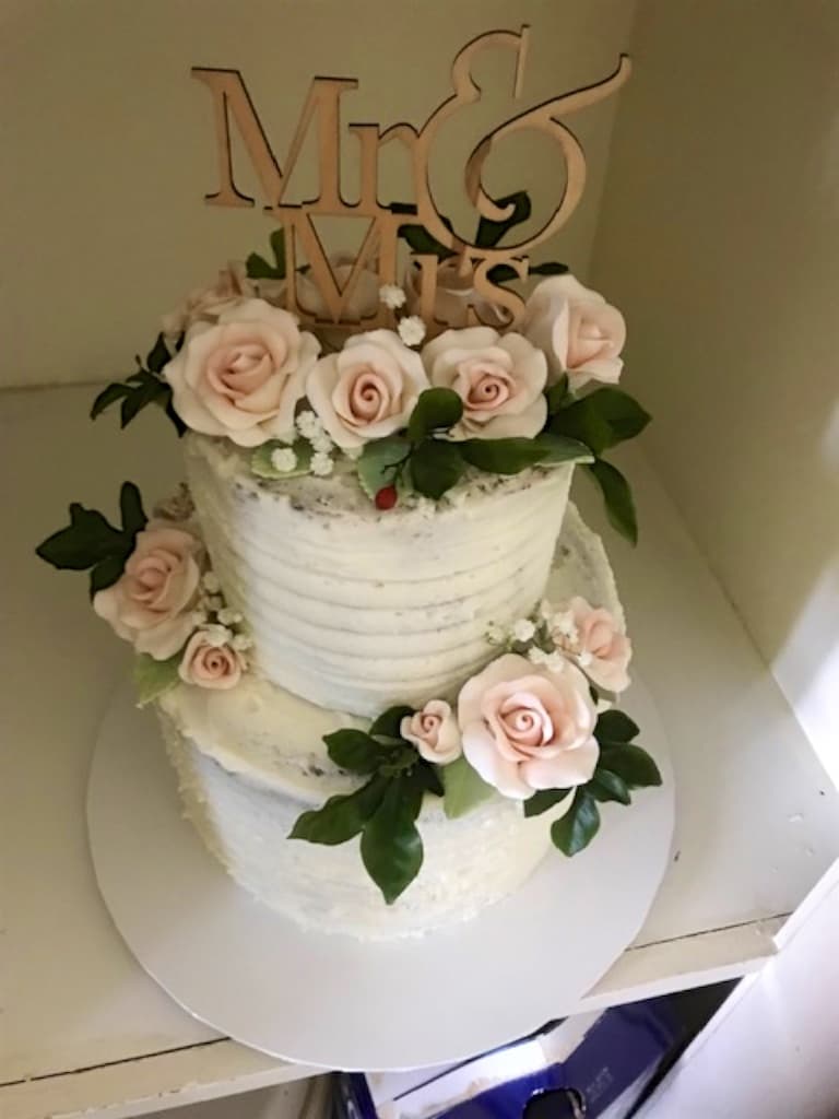Two-tier semi-naked wedding cake with sugar roses and a 'Mr & Mrs' topper